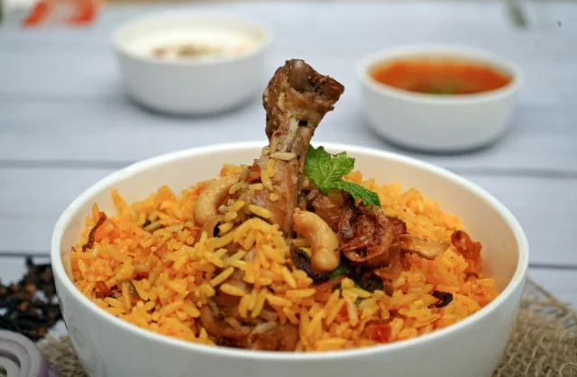 Chicken biryani with fried onions and cashews in a white ceramic bowl