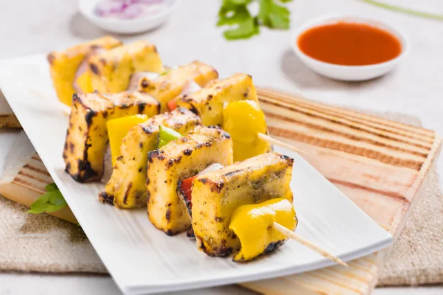 Grilled paneer and pepper skewers on a white ceramic plate